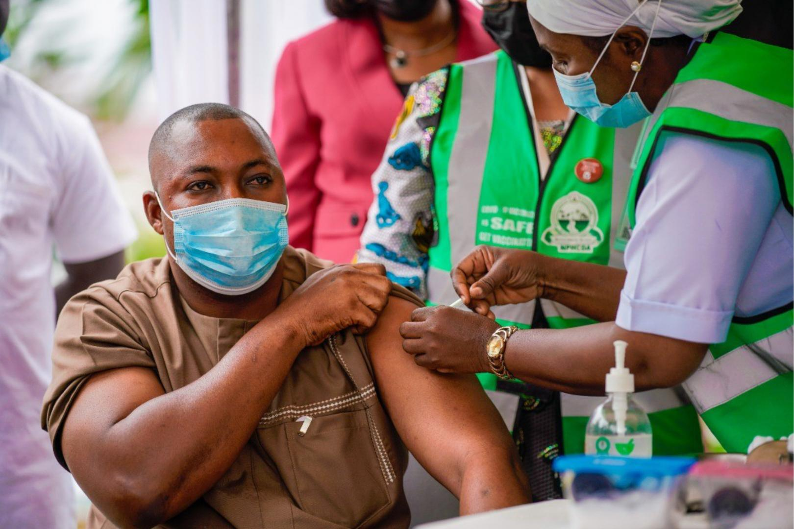 A man wearing a face mask receiving a vaccine from a healthcare worker